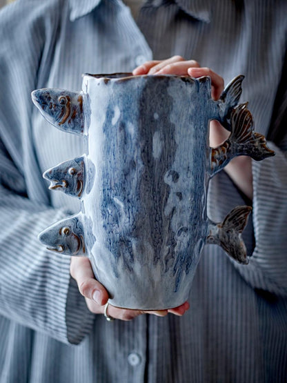 A person holding the Stoneware fish vase with three decorative fish and blue reactive glaze
