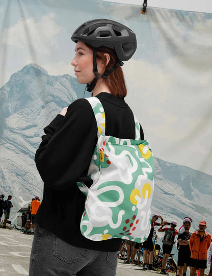 Person wearing a black helmet and carrying a colorful backpack with a mountainous background.