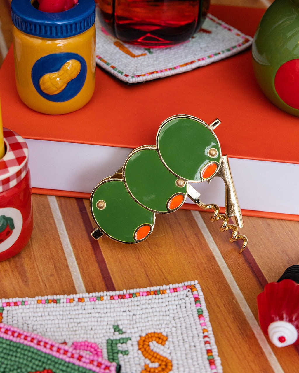 Olive corkscrew on a wooden surface with colorful items in the background
