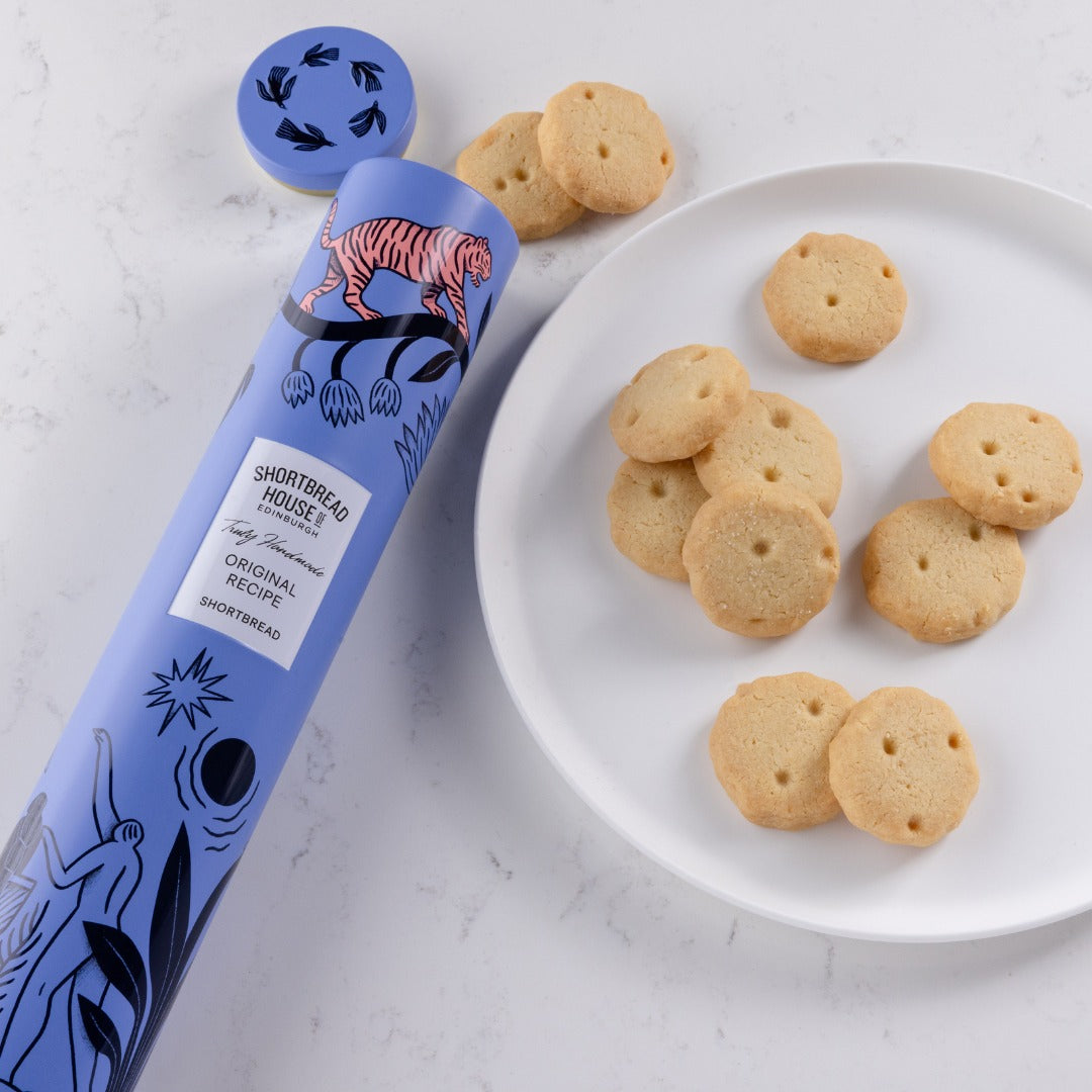 Blue packaging of Shortbread House cookies with a plate of shortbread cookies on a white surface