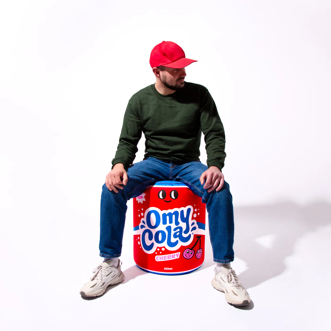 Person sitting on a Omy Cola Inflatable Pillow against a white background
