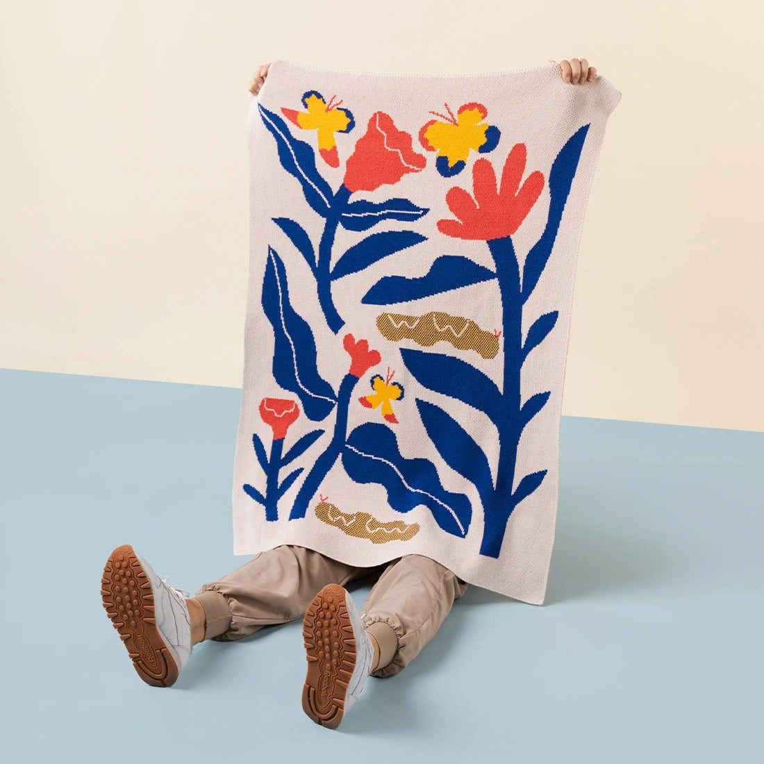 kid holding the Papillons Mini Blanket 30x40 inches, designed byAmélie Lehoux, made from 50% cotton and 50% recycled polyester, soft and eco-friendly, made in USA.