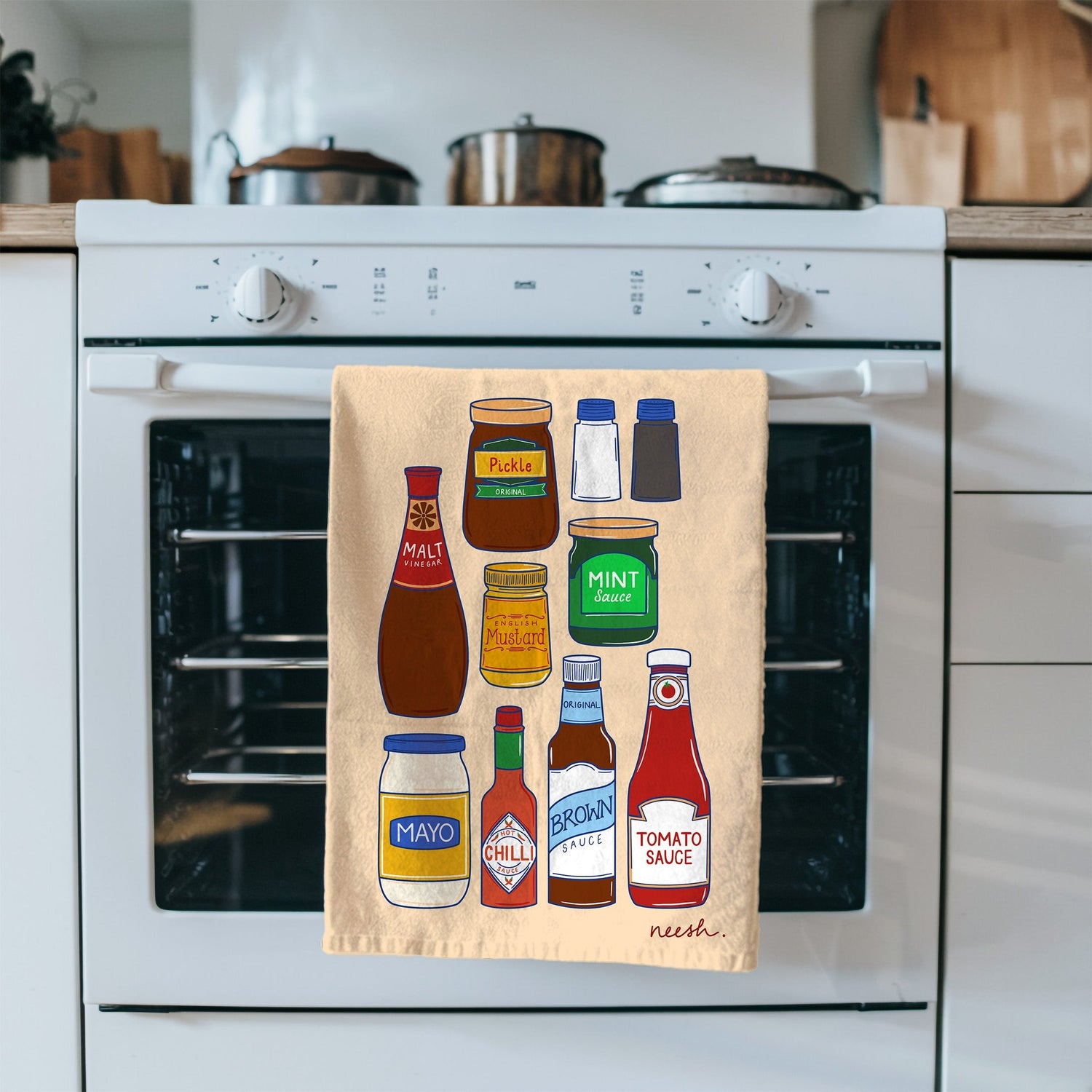 Kitchen towel with condiment illustrations hanging on a stove