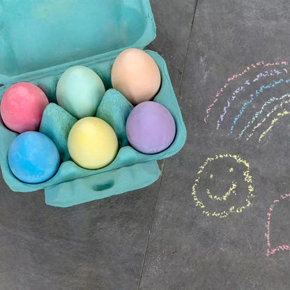 Colourful egg-shaped chalks in cardboard egg box for kids’ art on a charcoal background