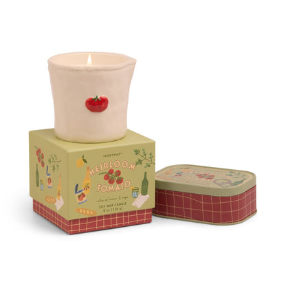 Tomato embossed 8oz ceramic candle with hand-painted tomato icons, emitting fresh savory and herbaceous fragrance, from the Bistro Collection, packaged in a charming sliding box. Next to it he Tomato candle in a tin