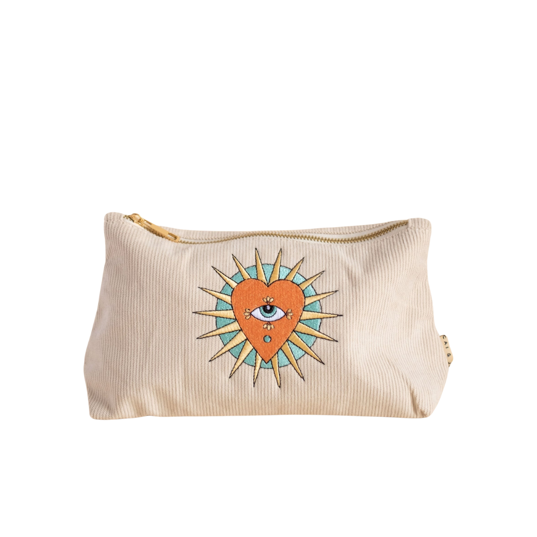 A beige corduroy pouch with a decorative pattern featuring a sun, heart and an eye on the front.