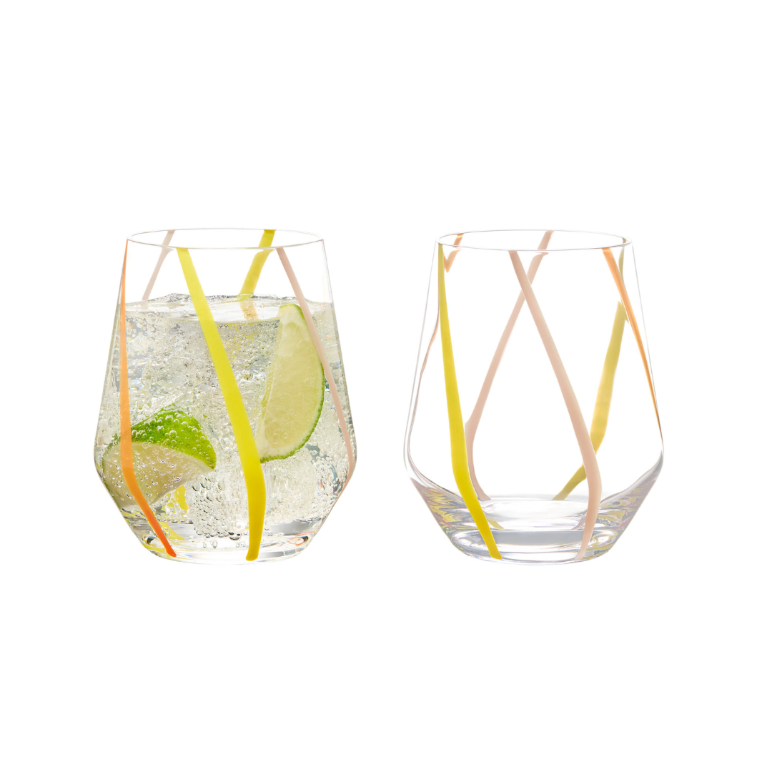 Two clear glass tumblers with handcrafted colorful (pink, orange, and yellow) swirl patterns on them, one with a citrus slice inside.