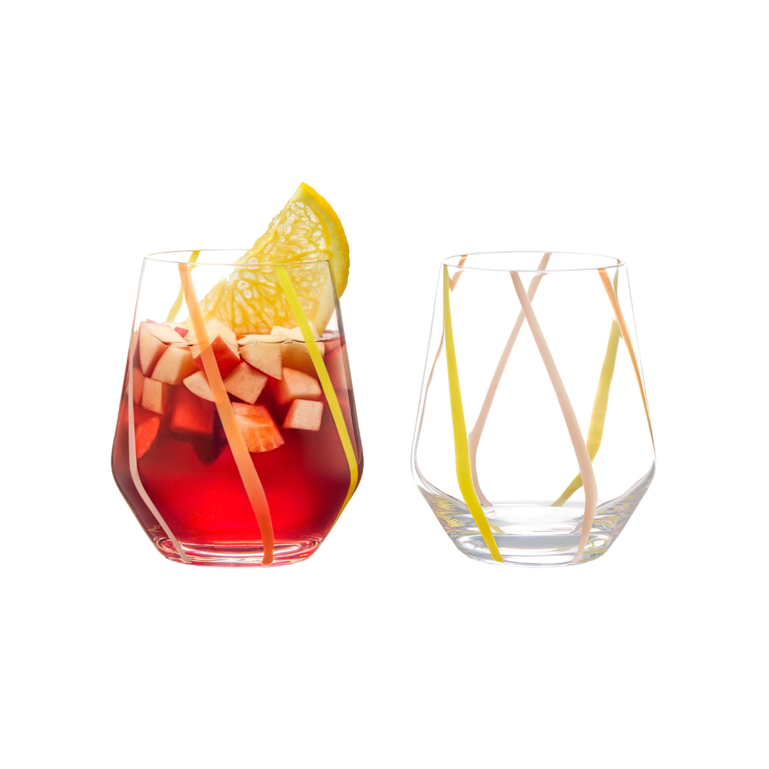 Two clear glass tumblers with handcrafted colorful (pink, orange, and yellow) swirl patterns on them, one with a citrus slice inside.