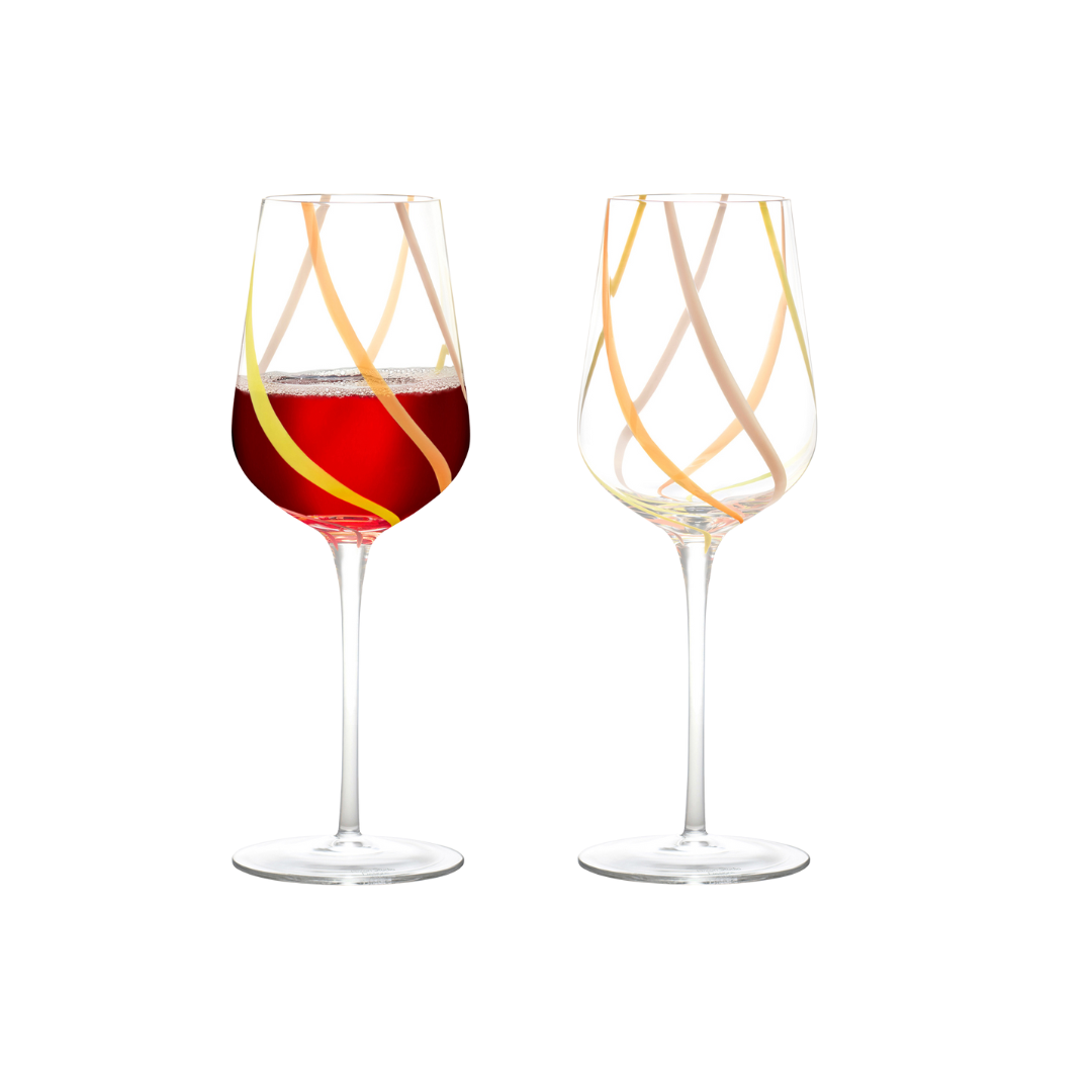 Handcrafted swirl wine glasses filled with red wine on a white background, featuring vibrant pink, orange, and yellow colors with long stems