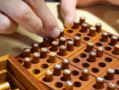 Close-up of a hand playing the wooden Sudoku puzzle game