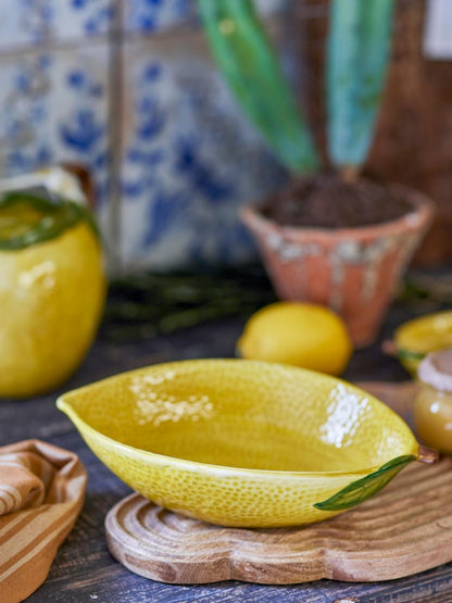 Limone Bowl made of yellow stoneware with lemon peel-inspired texture on a wooden surface