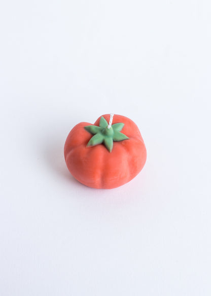 Tomato-shaped candle with green stem on a white background