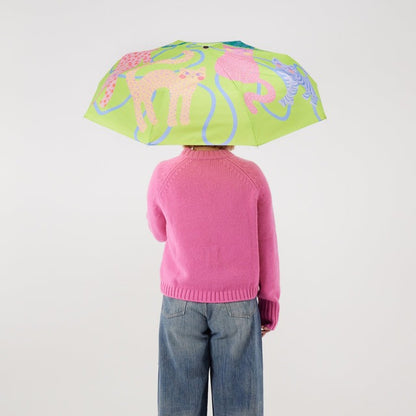 Person wearing a pink sweater and blue jeans holding a lime umbrella with cat designs on a white background