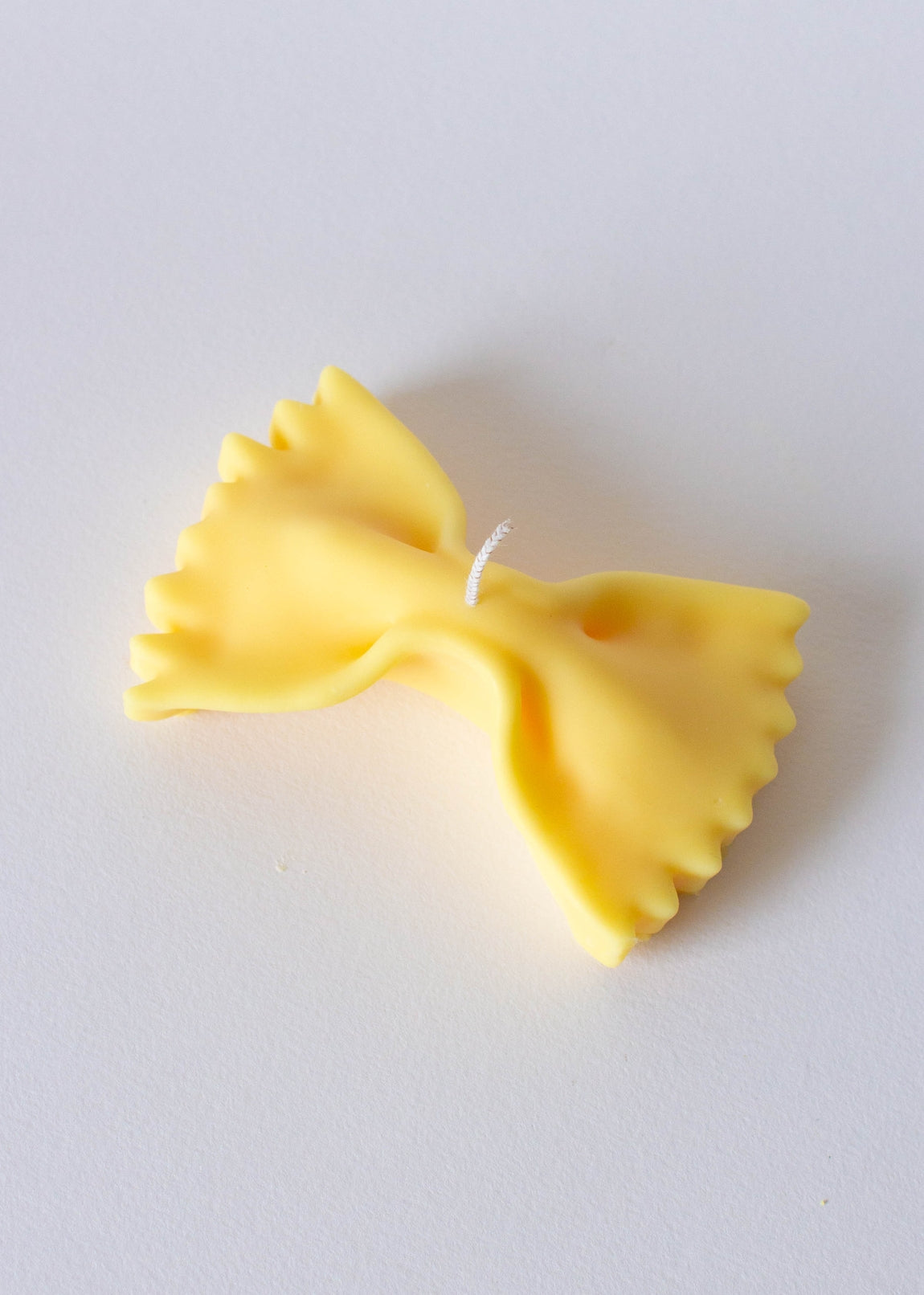 Yellow farfalla-shaped candle on a white background