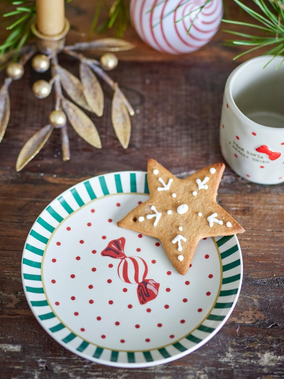 Green striped Caramella dessert plate with red caramel motif, displayed on a table with a festive cookie on top, hand-painted and perfect for serving desserts.
