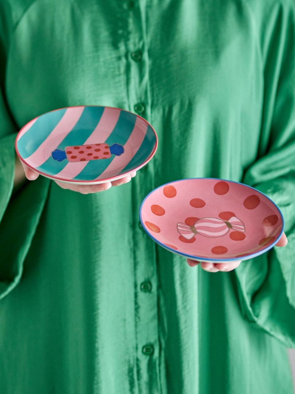 Two small ceramic plates with colorful caramella designs held by a person wearing a green shirt.