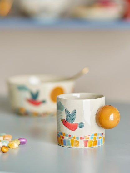 Decorative mug with a colorful design and round handle on a light surface.