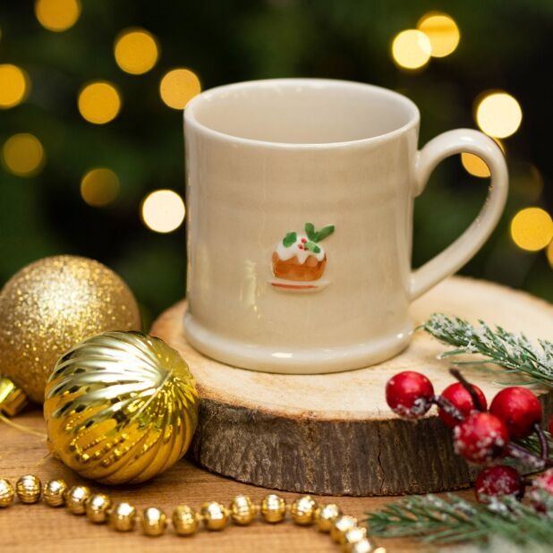 Mini Mug – Plum Pudding featuring a festive Christmas pudding design on a wooden surface with Christmas decorations.