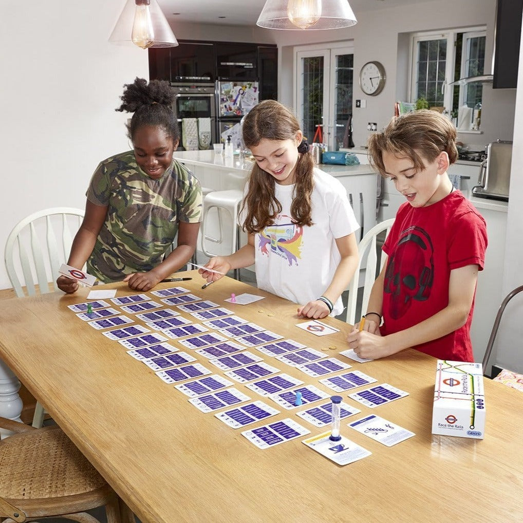 Three children playing the race the rails  game at a kitchen table.