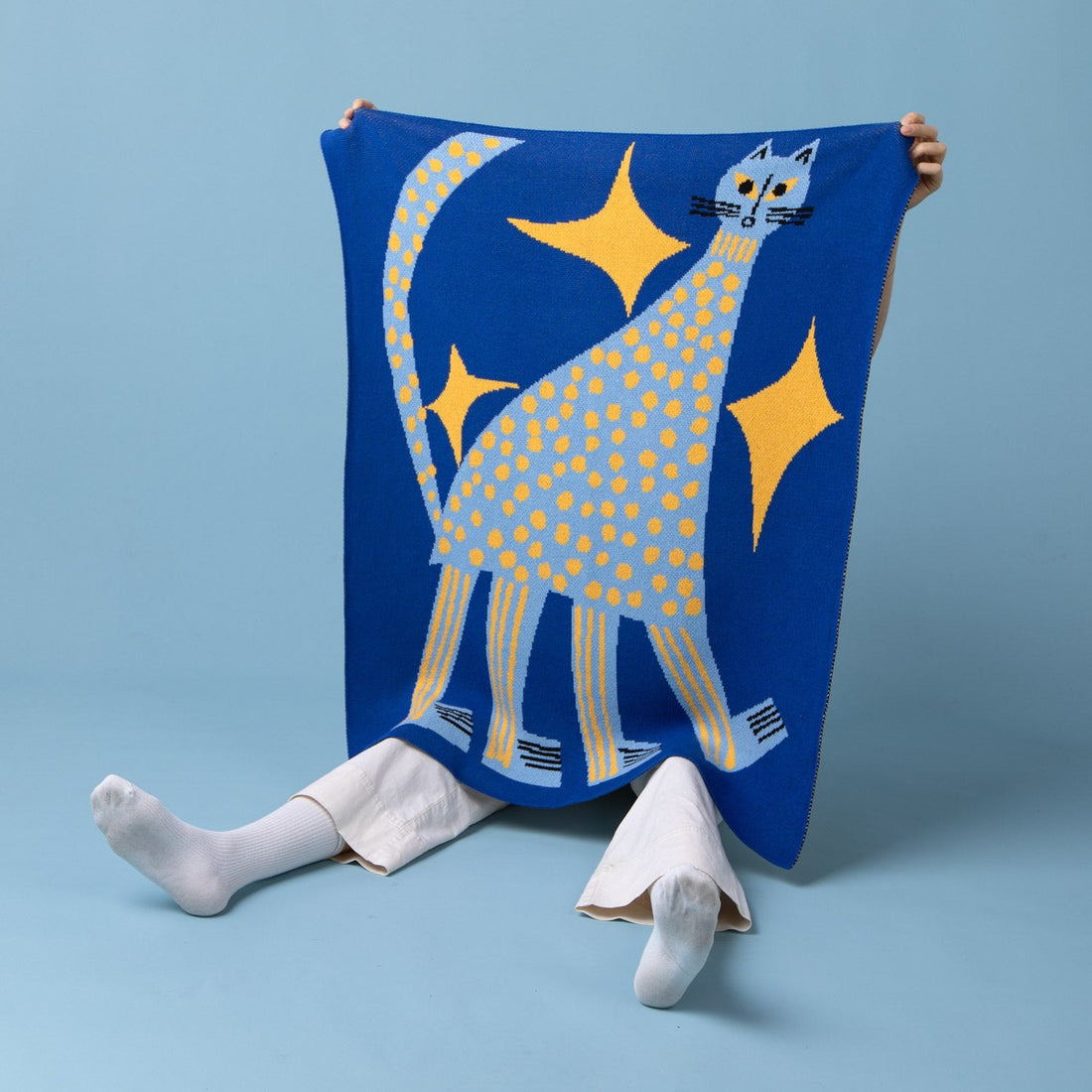 A little jid holding the Starry Night Mini Blanket 30x40 inches, designed by Marcello Velho, made from 50% cotton and 50% recycled polyester, soft, durable, eco-friendly, made in USA, perfect for babies