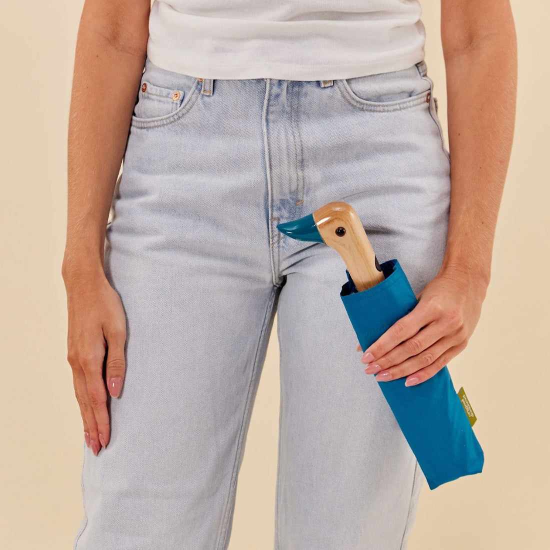 A person holding the teal duck compact umbrella